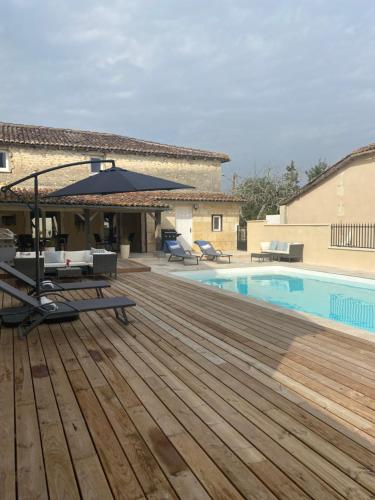 une piscine avec une terrasse en bois à côté d'une maison dans l'établissement La Rocque, à Saint-Sulpice-de-Cognac
