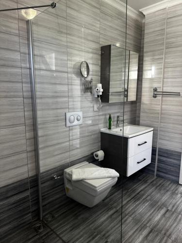a bathroom with a toilet and a glass shower at MG Pansiyon in Fethiye