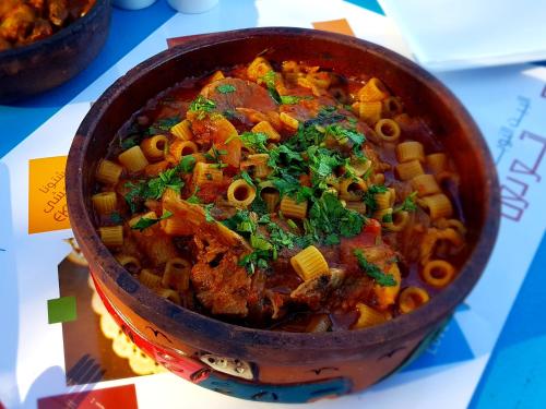 a bowl of food with pasta and vegetables on a table at Dolty Kato Nubian House By Kato Dool in Aswan