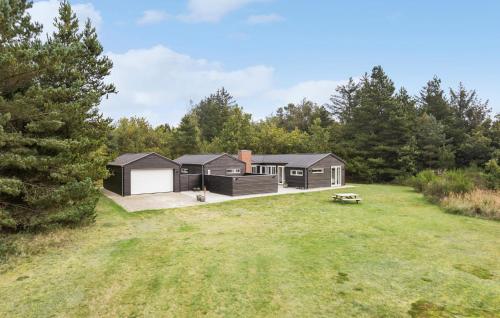 a black house in the woods with a yard at 4 Bedroom Cozy Home In Ålbæk in Ålbæk
