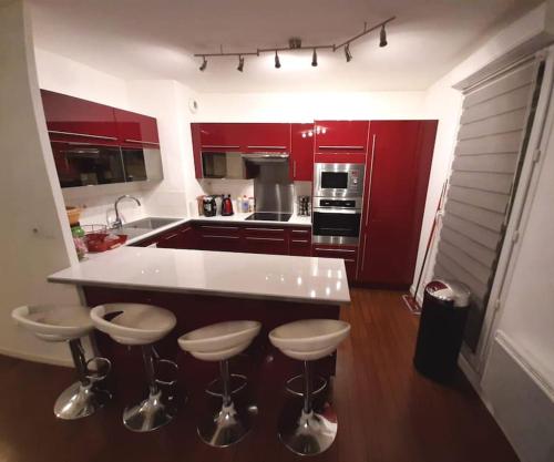 a kitchen with red cabinets and a island with bar stools at Joli appartement avec Jardin et 2 parkings privés in Argenteuil
