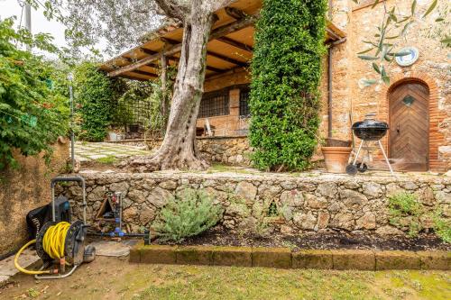 a stone house with a tree and a grill at Greg's House in Santa Lucia