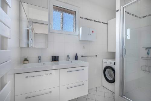 een witte badkamer met een wastafel en een wasmachine bij Appart vue mer pour 4 à St Brevin les Pins in Saint-Brevin-les-Pins