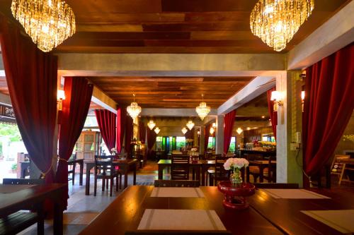 a dining room with tables and chairs and chandeliers at Thai Thai Sukhothai Resort in Sukhothai