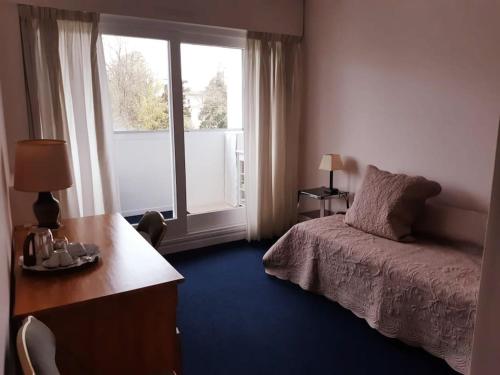 une chambre avec un lit, un bureau et une fenêtre dans l'établissement Appartement avec jardin et Tennis, à Saint-Cloud