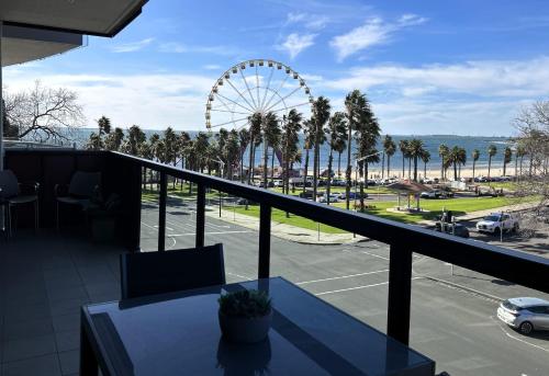 a balcony with a table and a ferris wheel at PROMENADE TOWERS 3 Bedroom Apartment with Bay Views on the Geelong Waterfront - 403 in Geelong