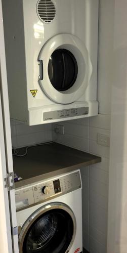 a microwave above a washing machine in a kitchen at PROMENADE TOWERS 3 Bedroom Apartment with Bay Views on the Geelong Waterfront - 403 in Geelong