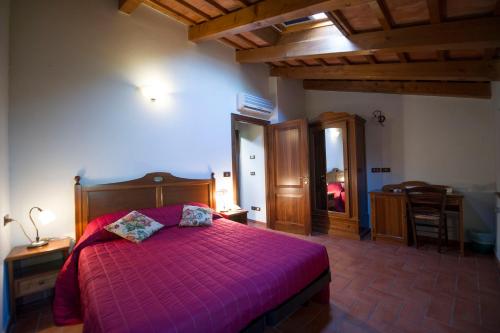 a bedroom with a bed with a purple comforter at Il Podere Del Germano Reale in Coriano