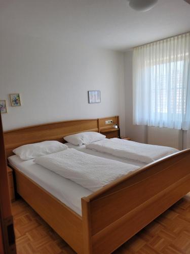 a bedroom with a bed with white sheets and a window at Gästehaus-zum-See in Bad Buchau