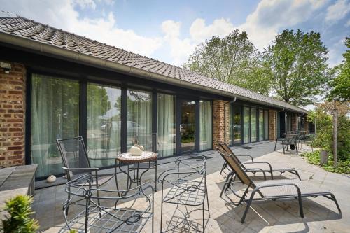 a patio with chairs and a table and some windows at Meschermolen in Mesch
