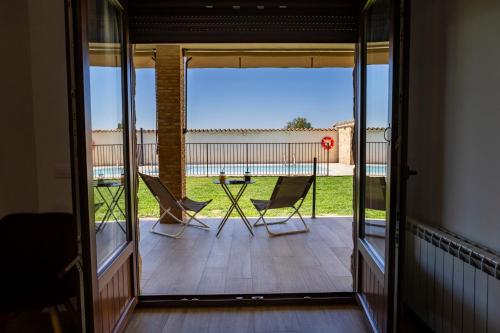 a view of a balcony with two chairs and a table at Apartamentos rurales Posada de Monfragüe con jacuzzi in Malpartida de Plasencia