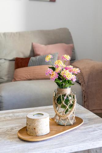 a vase with flowers on a table in a living room at Apartamentos rurales Posada de Monfragüe con jacuzzi in Malpartida de Plasencia