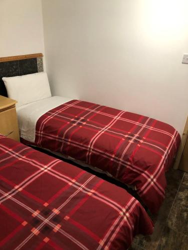 2 camas en una habitación con una manta roja a cuadros en Seven Dials Hotel, en Londres