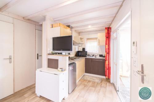 Il comprend une cuisine avec des placards blancs et une télévision. dans l'établissement Parc résidentiel les vignes, à Lit-et-Mixe