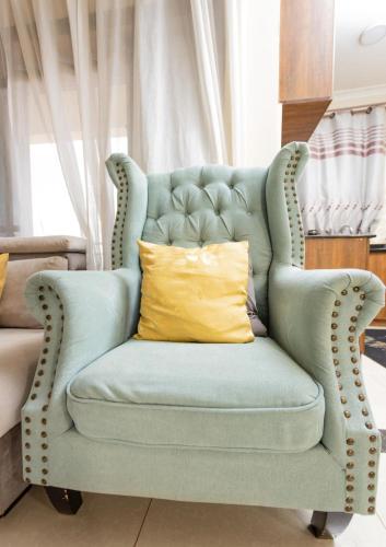 a blue chair with a yellow pillow in a room at Mayfair 1 Bedroom-Bukoto in Kampala