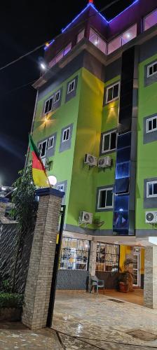 a green building with a flag in front of it at Ma'a Lapseu hôtel in Yaoundé