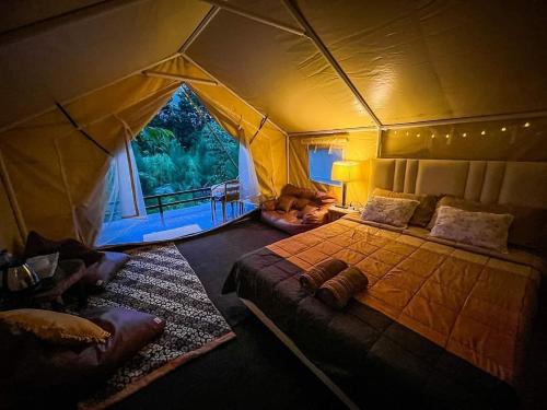 a bedroom with a tent with a bed and a couch at โดมอิงธาร บ้านสวนสราญชล in Ban Plai Nam (2)