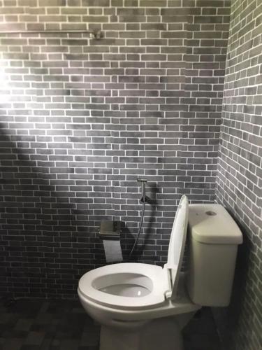 a bathroom with a white toilet in a brick wall at โดมอิงธาร บ้านสวนสราญชล in Ban Plai Nam (2)