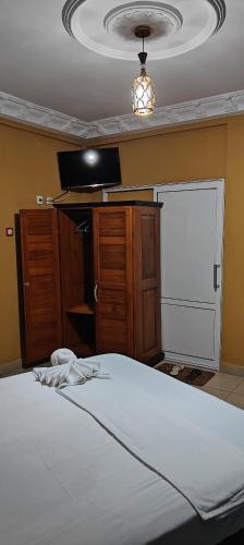 a bedroom with a bed and a television and a closet at Ma'a Lapseu hôtel in Yaoundé