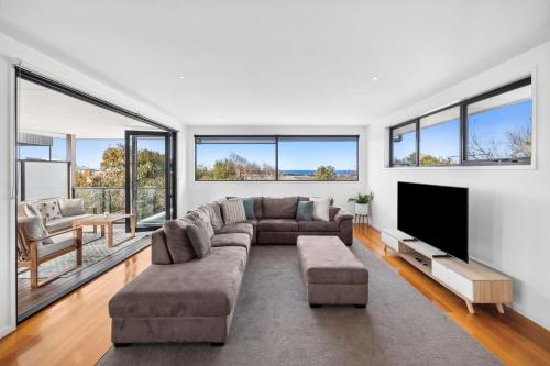 a living room with a couch and a flat screen tv at Torquay Point White-Water Retreat in Torquay
