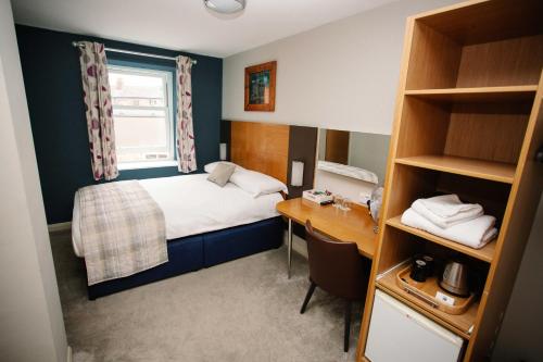 a small room with a bed and a desk at The Corner House Hotel in Taunton