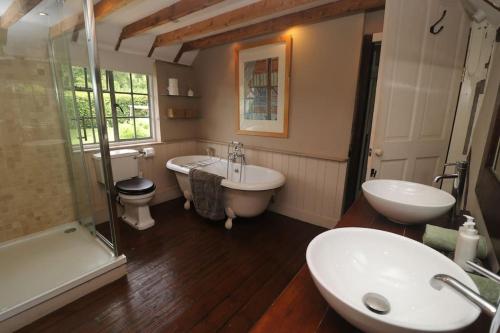 a bathroom with two sinks and a tub and a toilet at Idyllic 15th century farmhouse with hot tub in Petham