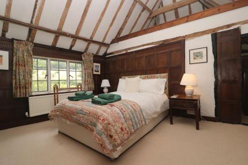 a bedroom with a bed with a green blanket on it at Idyllic 15th century farmhouse with hot tub in Petham