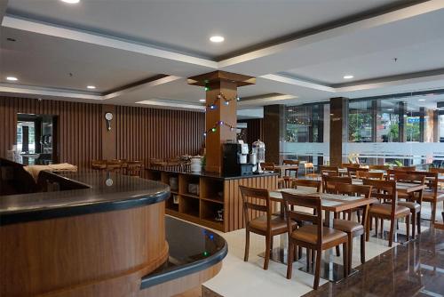 a restaurant with wooden tables and chairs and a bar at Favor Hotel Pekanbaru City Center in Pekanbaru
