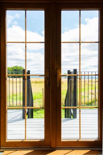an open door with a view of a balcony at Head For The Hills Glamping - Skylark Shepherd's Hut in Llanfynydd