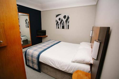 a small bedroom with a bed and a mirror at The Corner House Hotel in Taunton