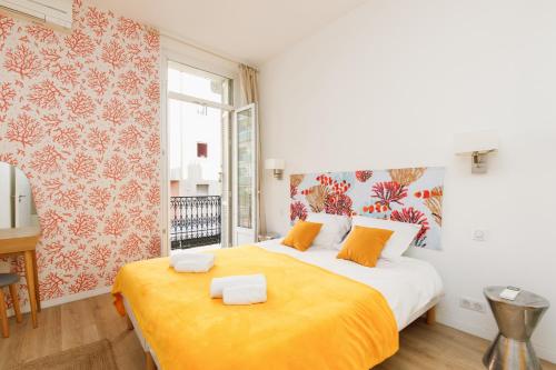 une chambre avec un grand lit avec une couverture orange dans l'établissement Nasturtium YourHostHelper, à Cannes