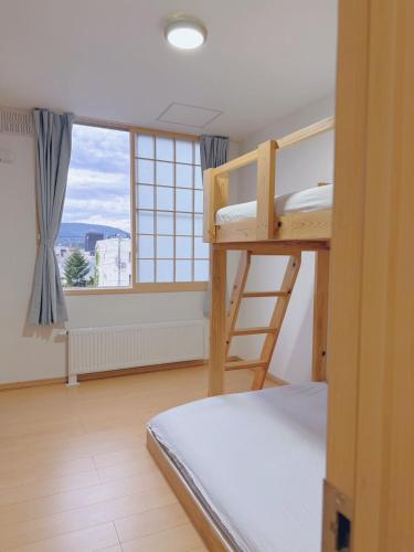 a room with two bunk beds and a window at Otaru Garden Stay in Otaru