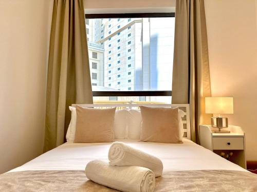 a bed with a towel on it with a window at Beautiful 2BR & 4BR Apartments on JBR Beach, Walking Distance to Bluewaters Island - By Sunkissed Holiday Homes in Dubai