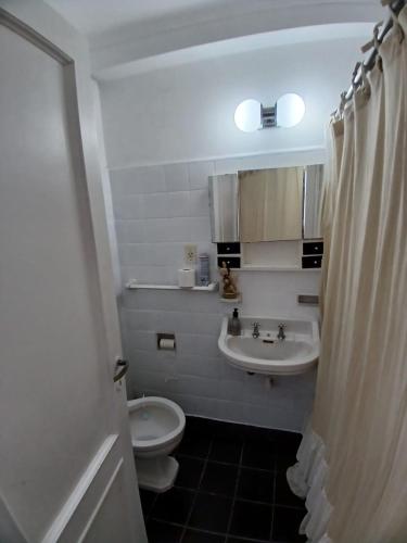 a bathroom with a toilet and a sink and a shower curtain at Departamento COSTAMAR in Miramar