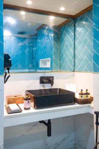 a bathroom with a sink and blue tiled walls at Alaya Stays 3 BHK With Garden - Evaara Woods Breeze in Shimla
