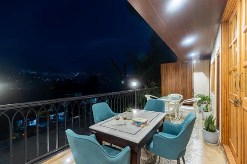 a patio with a table and chairs on a balcony at Alaya Stays 3 BHK With Garden - Evaara Woods Breeze in Shimla