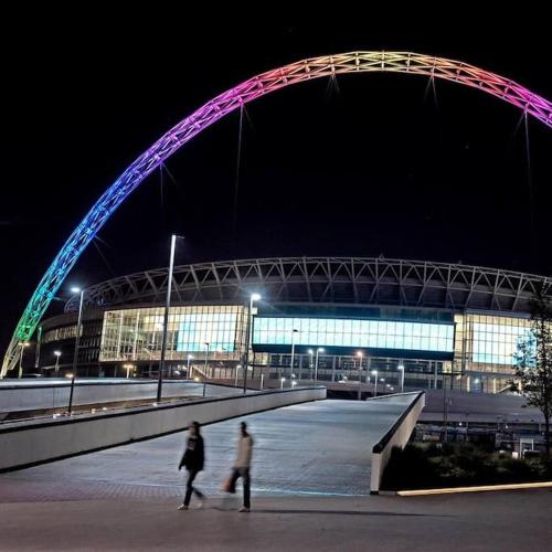 two people walking under a bridge in front of a building at Wembley Stadium and OVO Arena Apartment in London