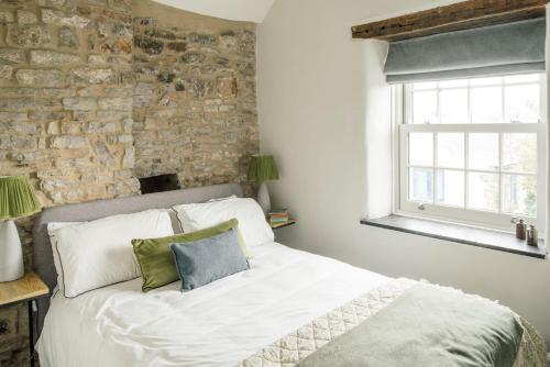 a bed in a bedroom with a stone wall at Sweet Pea Cottage in Tideswell
