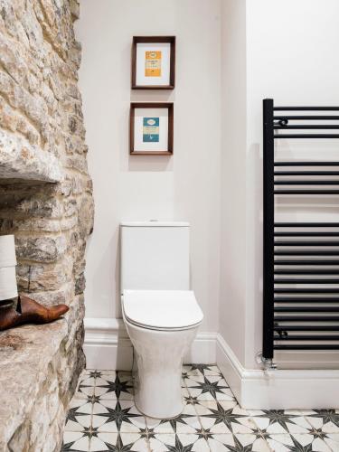 a white toilet in a bathroom with a stone wall at Sweet Pea Cottage in Tideswell