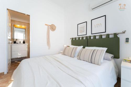 a bedroom with a large white bed with a green headboard at Linda House in Maspalomas