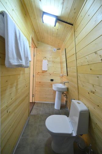 a wooden bathroom with a toilet and a sink at Hidden Garden Resort in Garni