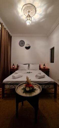 a bedroom with a bed and a table with flowers on it at Riad Dar Fatna in Marrakesh