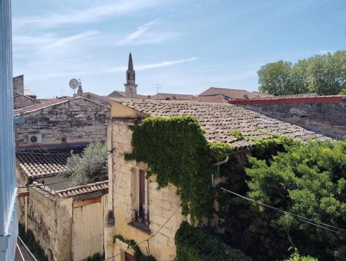an ivy covered building with a church in the background at Maison Intramuros 3 chambres 3 salles de bain - Idéal Festival in Avignon
