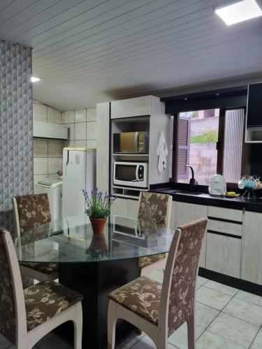 une cuisine avec une table et des chaises en verre dans l'établissement Casa Da Ju, à Lauro Müller