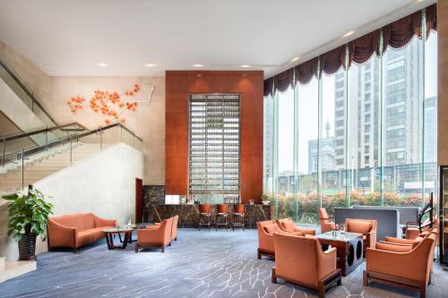 a lobby with orange chairs and tables and large windows at Crowne Plaza Zhenjiang by IHG in Zhenjiang