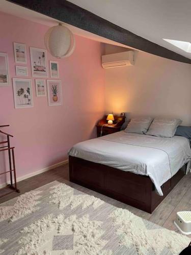 une chambre avec un lit et un mur rose dans l'établissement Bordeaux centre Maison calme, à Bordeaux