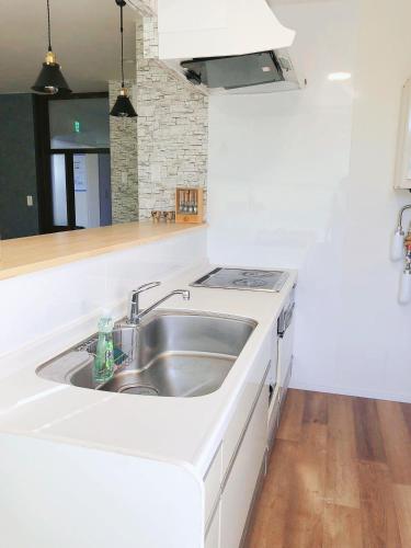 a white kitchen with a sink and a stove at Otaru Garden Stay in Otaru
