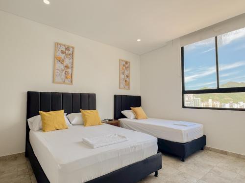two beds in a room with two windows at Apartasuites VITA 945 RODADERO - By Bedviajes in Santa Marta