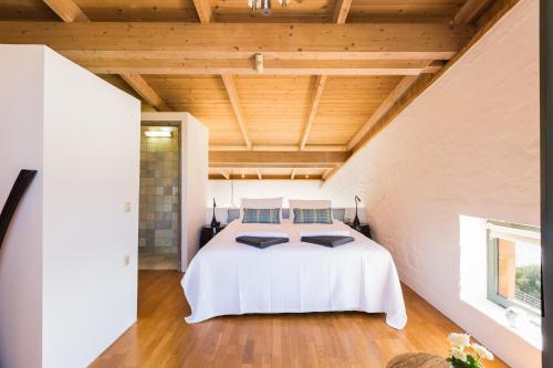 a bedroom with a white bed and a wooden ceiling at Yellow Dream Villas in Chorafakia
