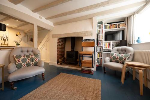 a living room with two chairs and a fireplace at Cosy cottage central Canterbury with free parking in Kent